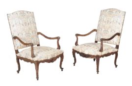 A pair of Continental carved walnut and upholstered armchairs