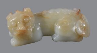 A Chinese celadon and russet jade &#8217;recumbent lion&#8217; carving