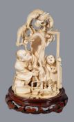 ϒ A Japanese Ivory Okimono of a Man and Boy with Dragon