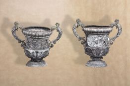 A pair of Victorian cast lead twin handled urns in Baroque style