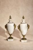 A pair of French white marble and gilt bronze mounted urns in Neoclassical style