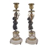 A pair of French patinated and parcel gilt bronze and marble mounted candlesticks