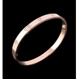 An 18 carat gold 'Love' bangle by Cartier, the polished bracelet with screw detail, ...