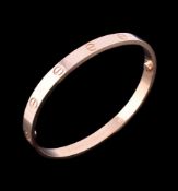 An 18 carat gold 'Love' bangle by Cartier, the polished bracelet with screw detail, ...