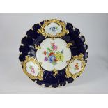 Meissen circular shallow Dish painted with panels of flowers within gilt cartouches and on a dark