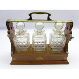 Edwardian three bottle tantalus in an inlaid mahogany and plated frame and fitted with three square