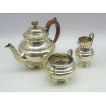 Silver three piece tea set of circular design, the teapot with stained handle and lift,