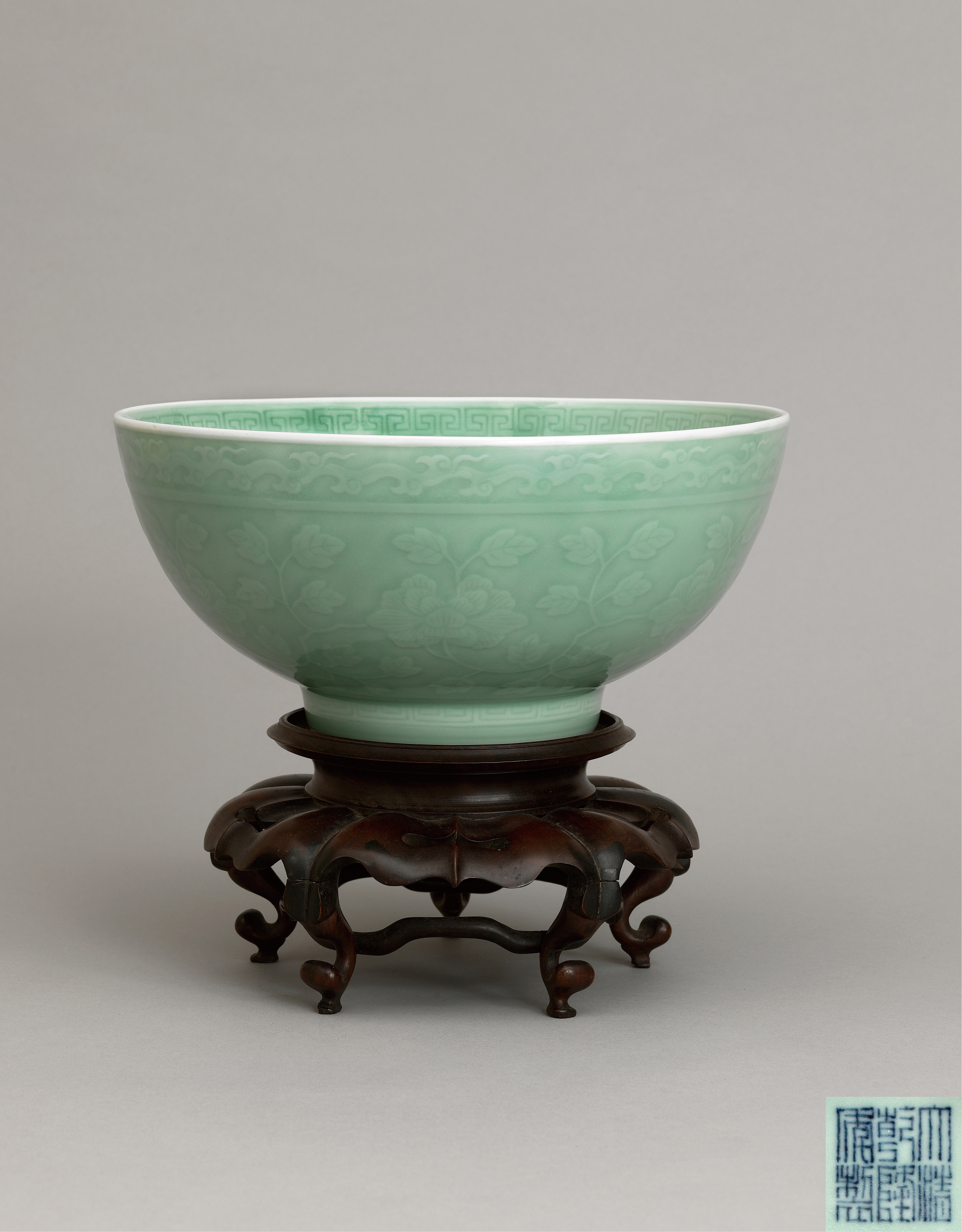 A large celadon-glazed ‘peony scroll' bowl,Qianlong six-character seal mark and of the period