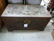 A Chinese Camphorwood Chest heavily carved all over with panels of figures, dragons, scrolls etc.