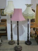 Three Traditional Wooden Standard Lamps with Fabric Shades, each with turned and decorated column
