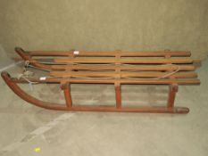 An Early Two Seat Sledge with curved metal runner supports and two strengthening frames. The