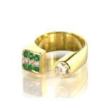 A modernist diamond and emerald dress ring in 18ct yellow gold, designed as an incomplete band,