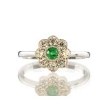 An emerald and diamond cluster dress ring in 18ct white gold, designed as a round cut emerald