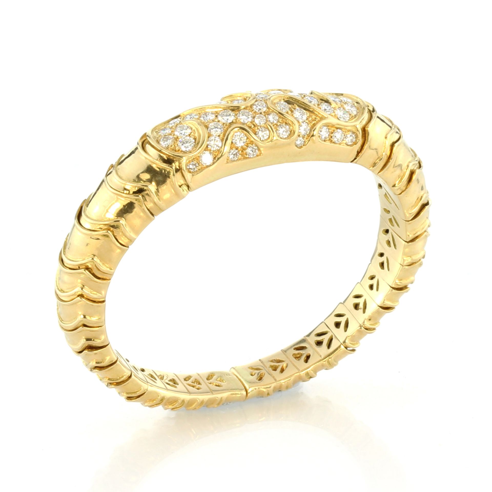 A French jewelled diamond bangle in 18ct yellow gold the sprung articulated body jewelled at the top