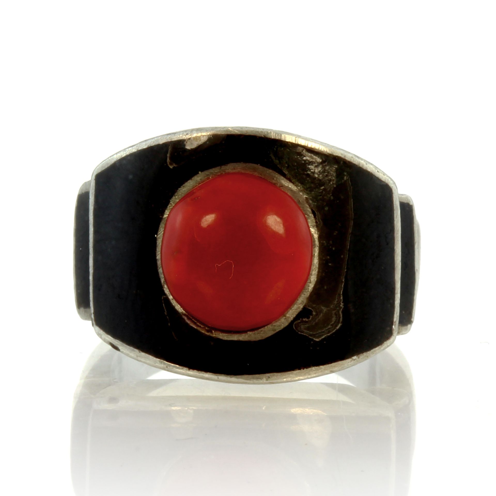 A vintage French coral and enamel dress ring in silver set with a central coral cabochon against a