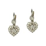 A pair of diamond cluster heart earrings in white gold or platinum, each set with a round cut