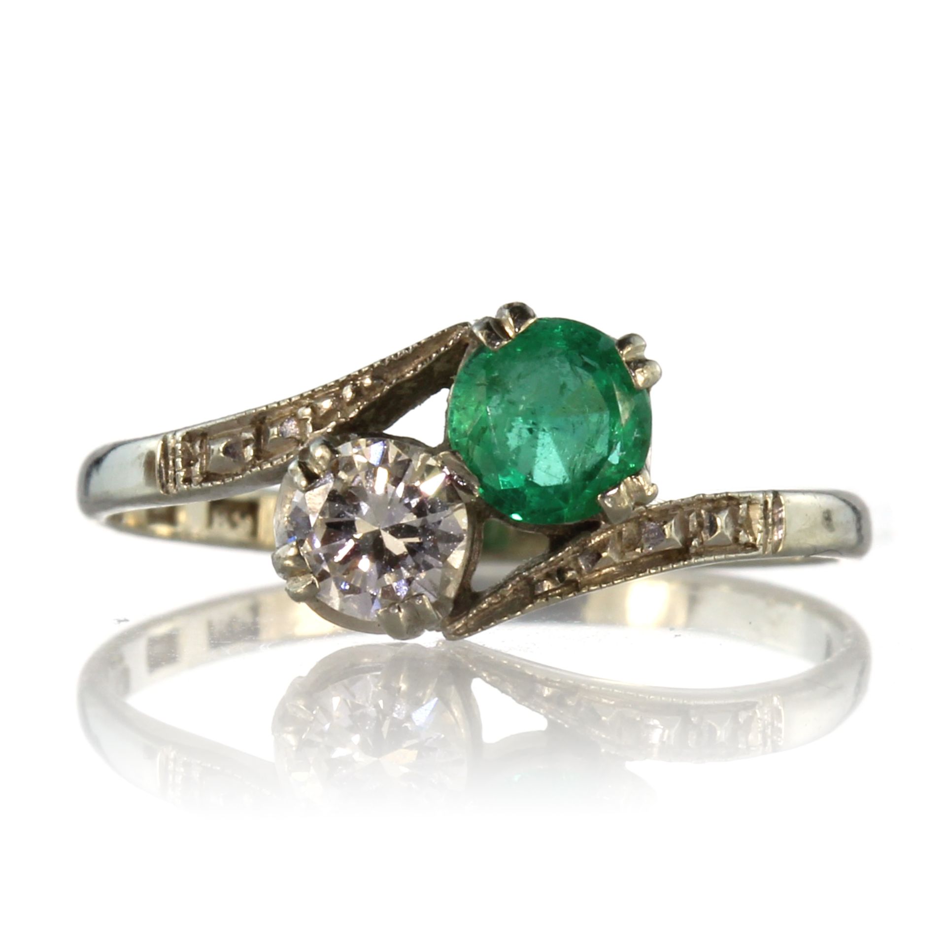 An antique Swedish emerald and diamond toi et moi crossover / twist ring in white gold, circa