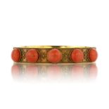 An antique coral bangle in 15ct yellow gold circa 1875, designed as a plain band set with five large