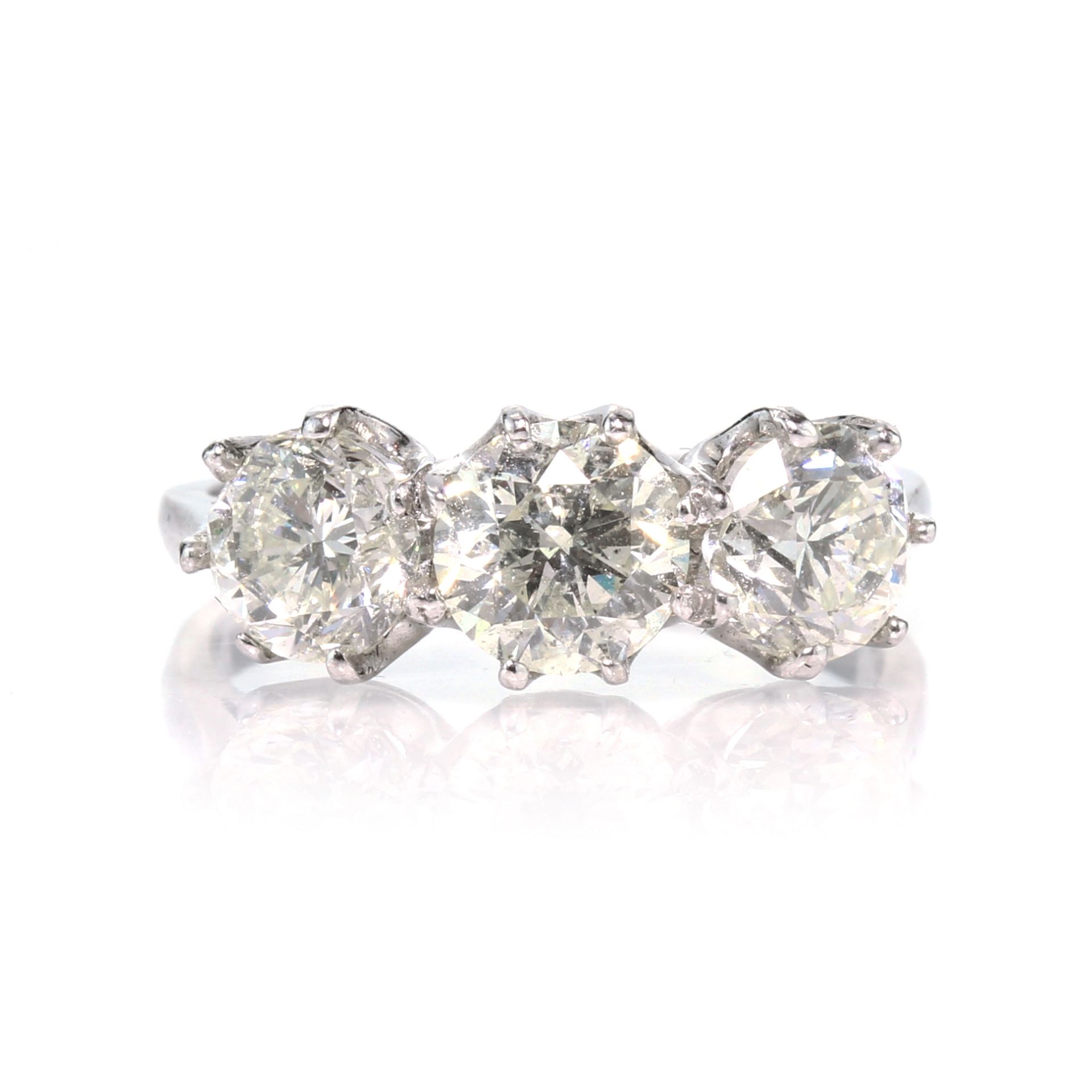 A diamond three stone dress ring in 18ct white gold set with three graduated round cut diamonds,