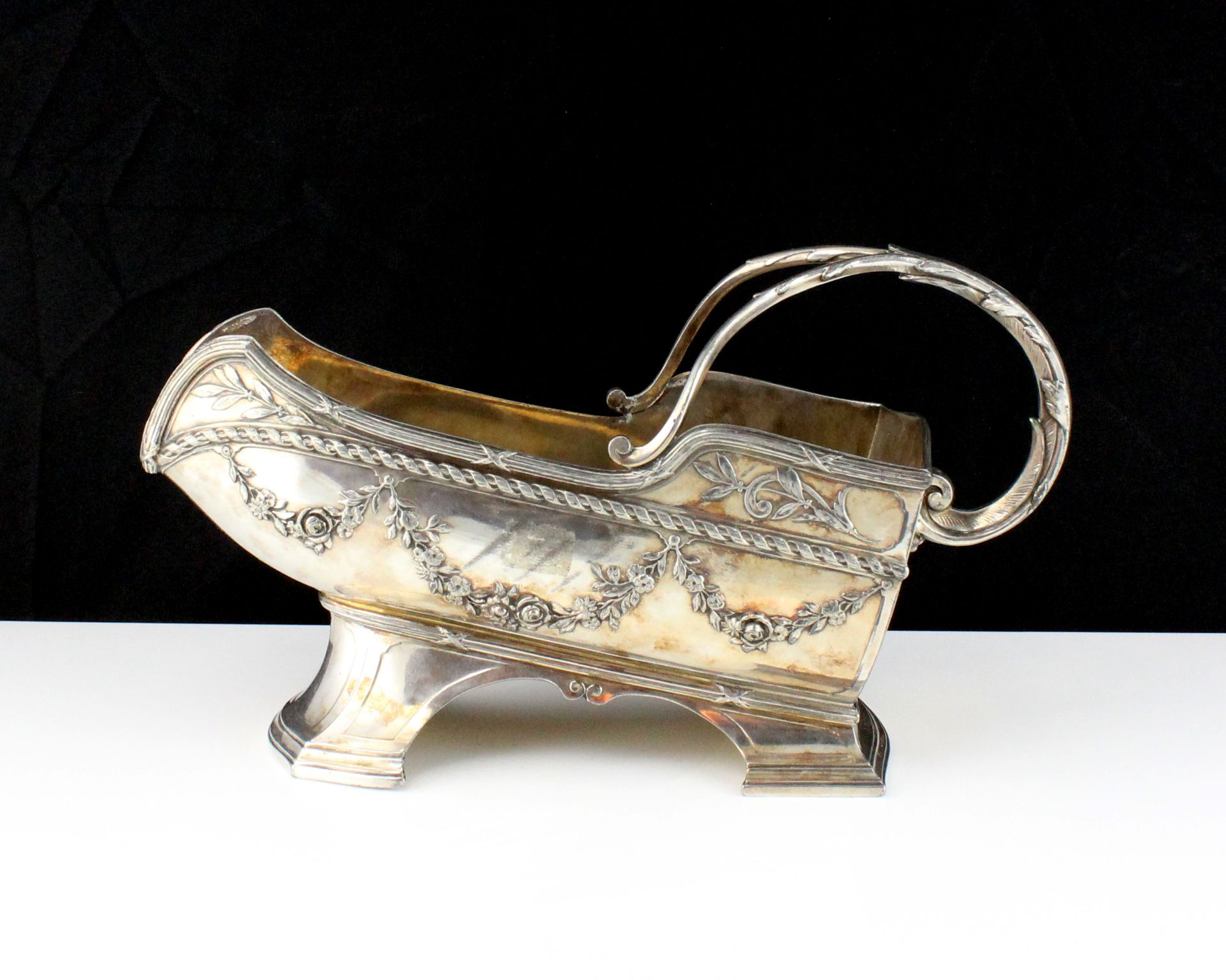 A French silver plated wine bottle holder, decorated with bound reeds and swags / garlands, with