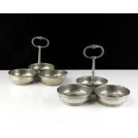 A pair of white metal condiment dishes each designed as a trio of circular dishes with a central