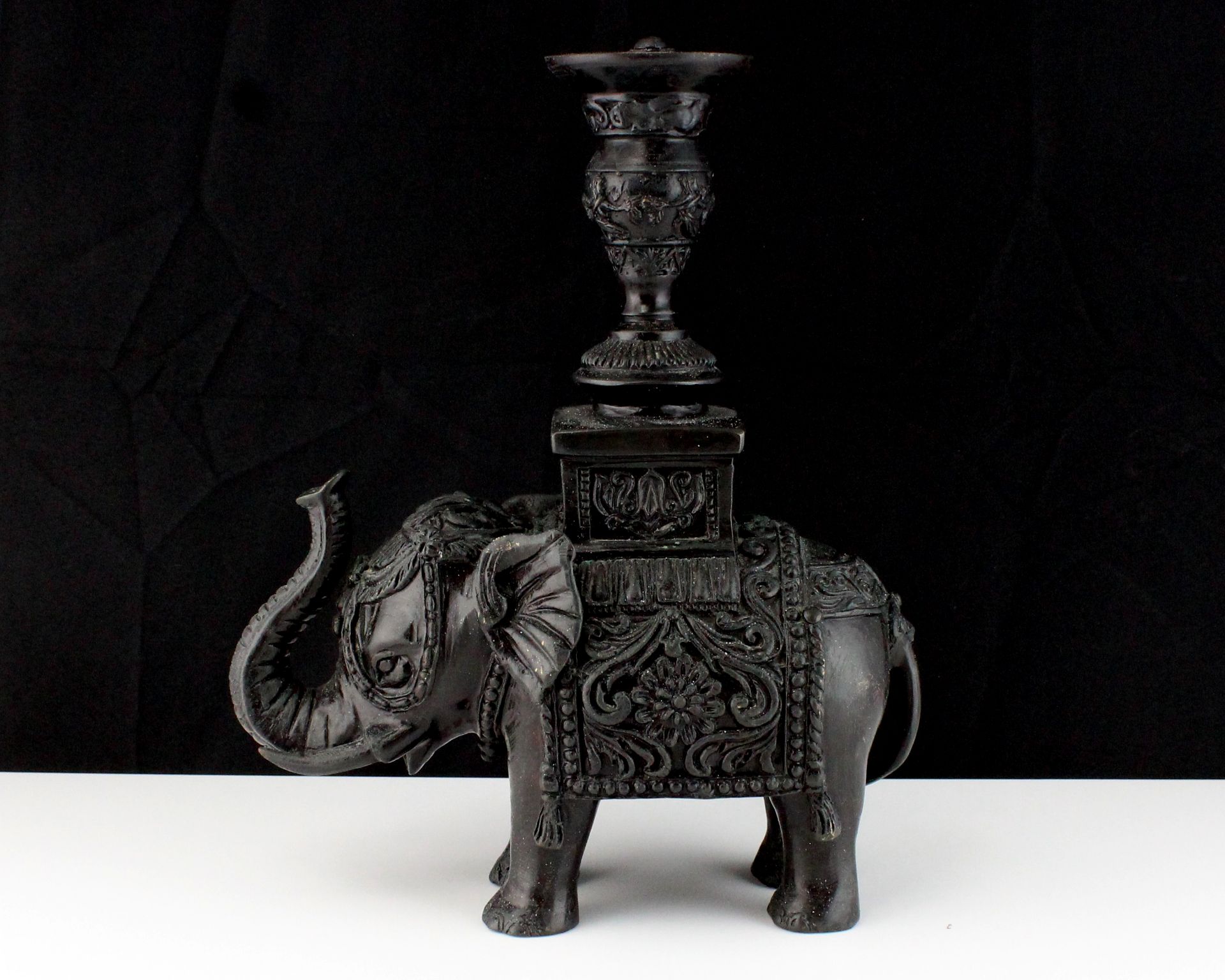 An oriental cast metal statue of an elephant carrying a pedestal on its back, suitable for