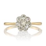 A DIAMOND CLUSTER DRESS RING set with a floral cluster of eight round cut diamonds on a tapering