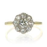 A DIAMOND CLUSTER DRESS RING set with a central round cut diamond encircled by eight further round