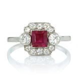 A RUBY AND DIAMOND DRESS RING set with a central square step cut ruby of 0.83 carats flanked on