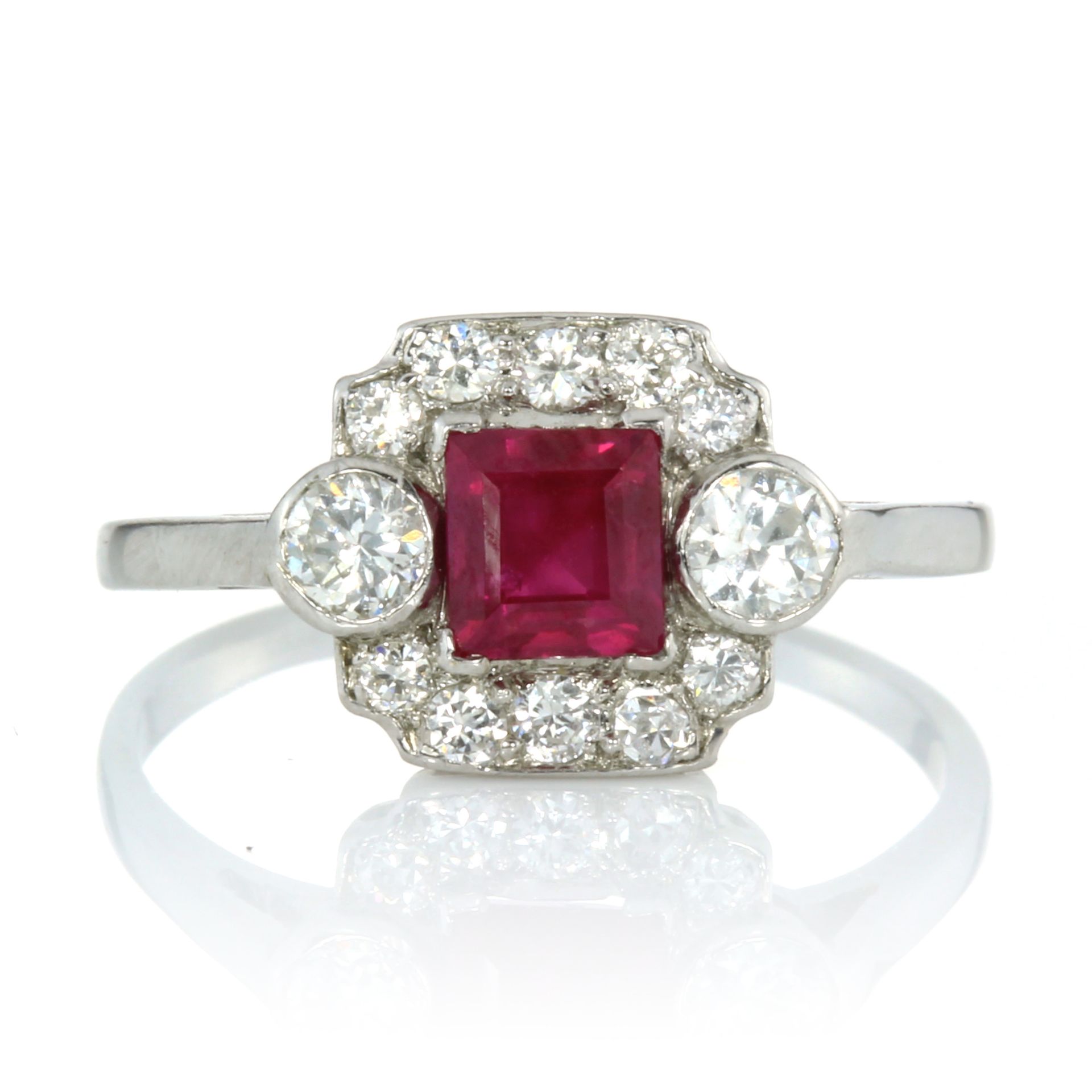 A RUBY AND DIAMOND DRESS RING set with a central square step cut ruby of 0.83 carats flanked on