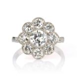 A DIAMOND CLUSTER DRESS RING designed as a floral cluster set with a central transitional cut