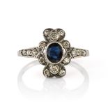 A SAPPHIRE AND DIAMOND DRESS RING set with a central oval cut sapphire surrounded by a floral