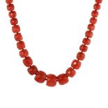 AN ANTIQUE FACETED CORAL BEAD NECKLACE comprising a single row of eighty-three faceted, graduated