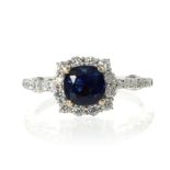 A SAPPHIRE AND DIAMOND CLUSTER RING set with a central cushion cut sapphire of 1.56 carats