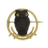 A WOODEN OWL BROOCH, EARLY 20TH CENTURY designed as a carved wooden owl with glass eyes, seated on a