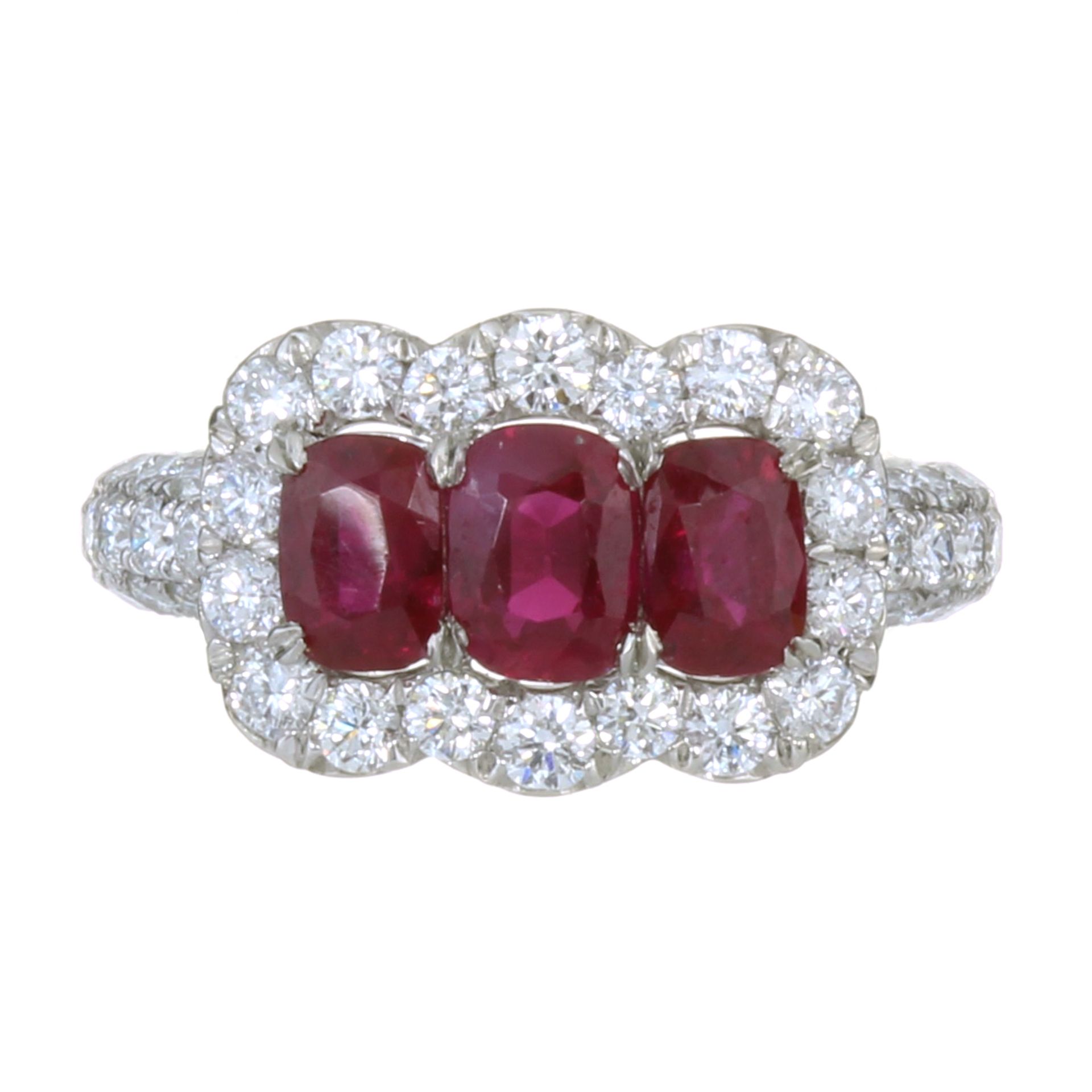 A BURMA NO HEAT RUBY AND DIAMOND DRESS RING in platinum set with three graduated oval cut rubies