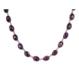 AN ANTIQUE AMETHYST RIVIERA NECKLACE in silver, comprising a single row of twenty-two oval cut