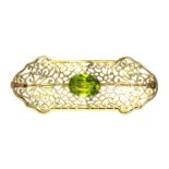 A JEWELLED ART DECO BROOCH in high carat yellow gold, set with a central oval cut green gemstone