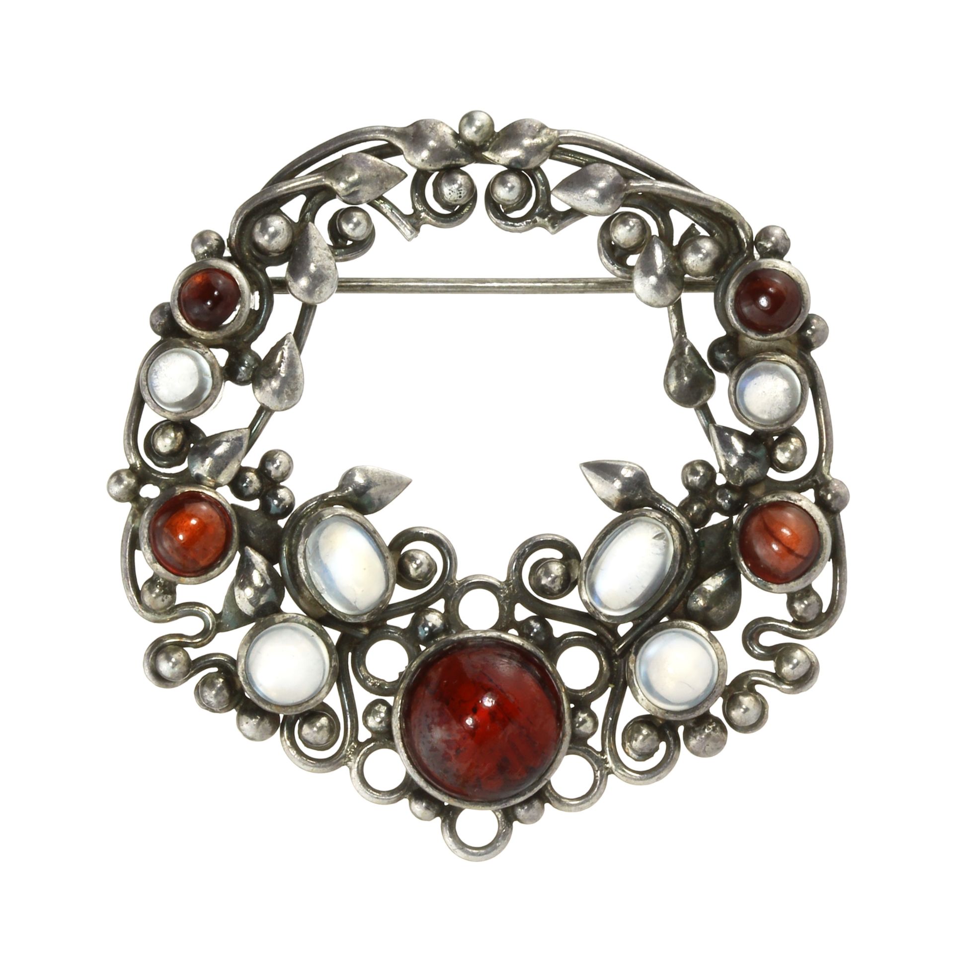 AN ANTIQUE ARTS & CRAFTS MOONSTONE AND GARNET BROOCH, ATTRIBUTED TO DORRIE NOSSITER in silver set