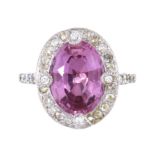 A PINK TOPAZ AND DIAMOND RING in platinum set with a central oval cut pink topaz of 6.25 carats