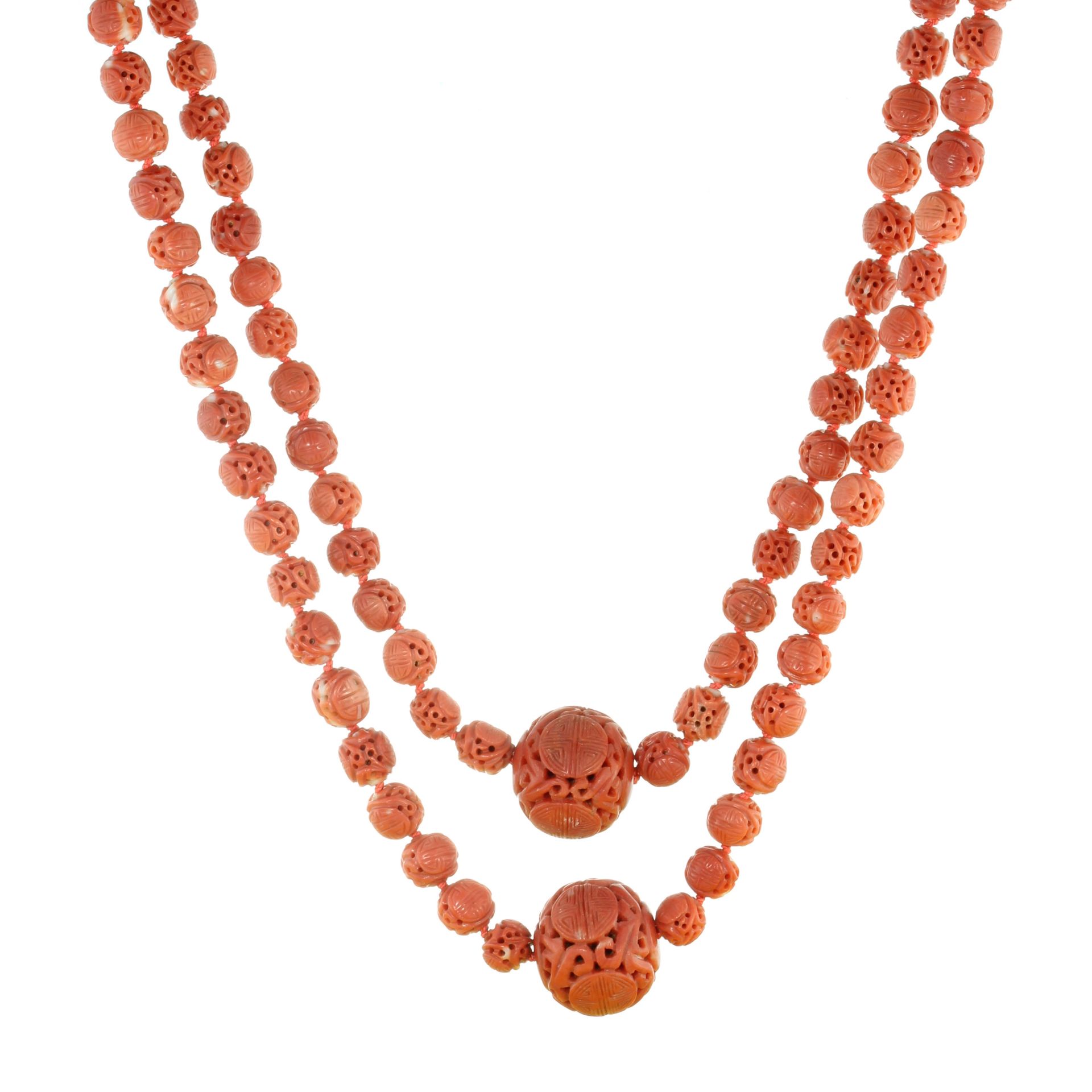 AN ANTIQUE CHINESE CARVED CORAL BEAD NECKLACE comprising four large beads of 21-24mm within a