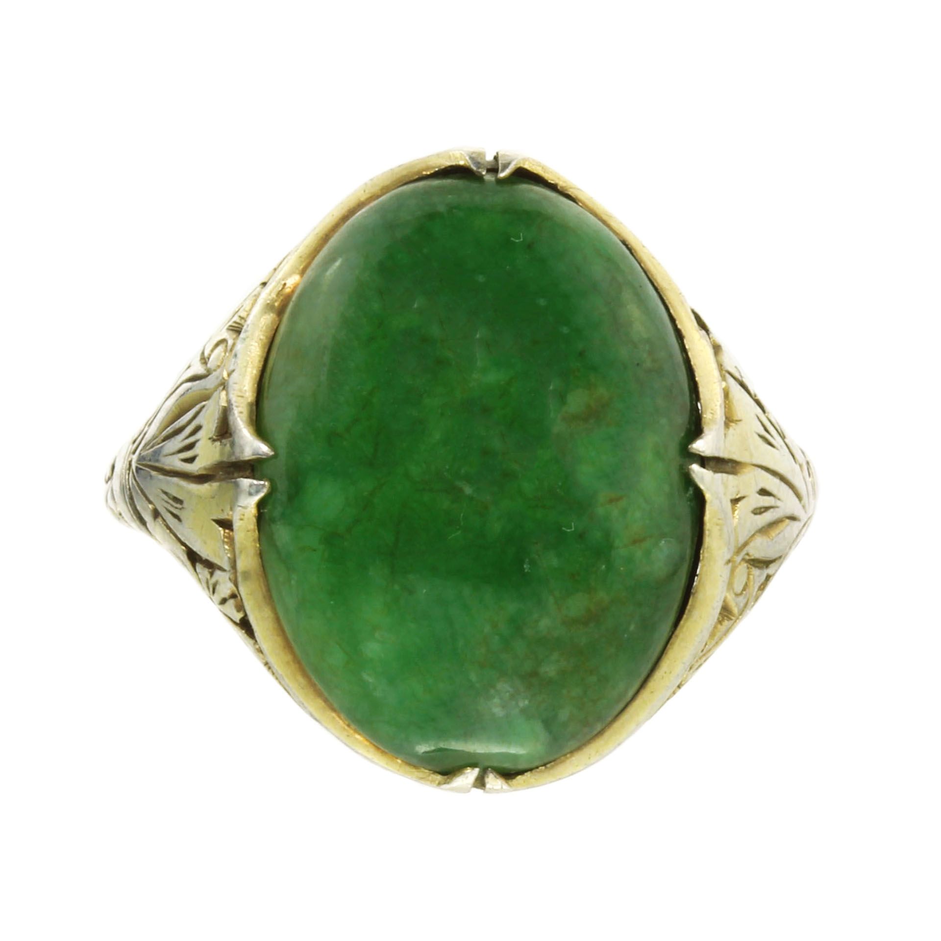 A JADEITE JADE RING set with a large piece of cabochon jade within a mount decorated with pierced