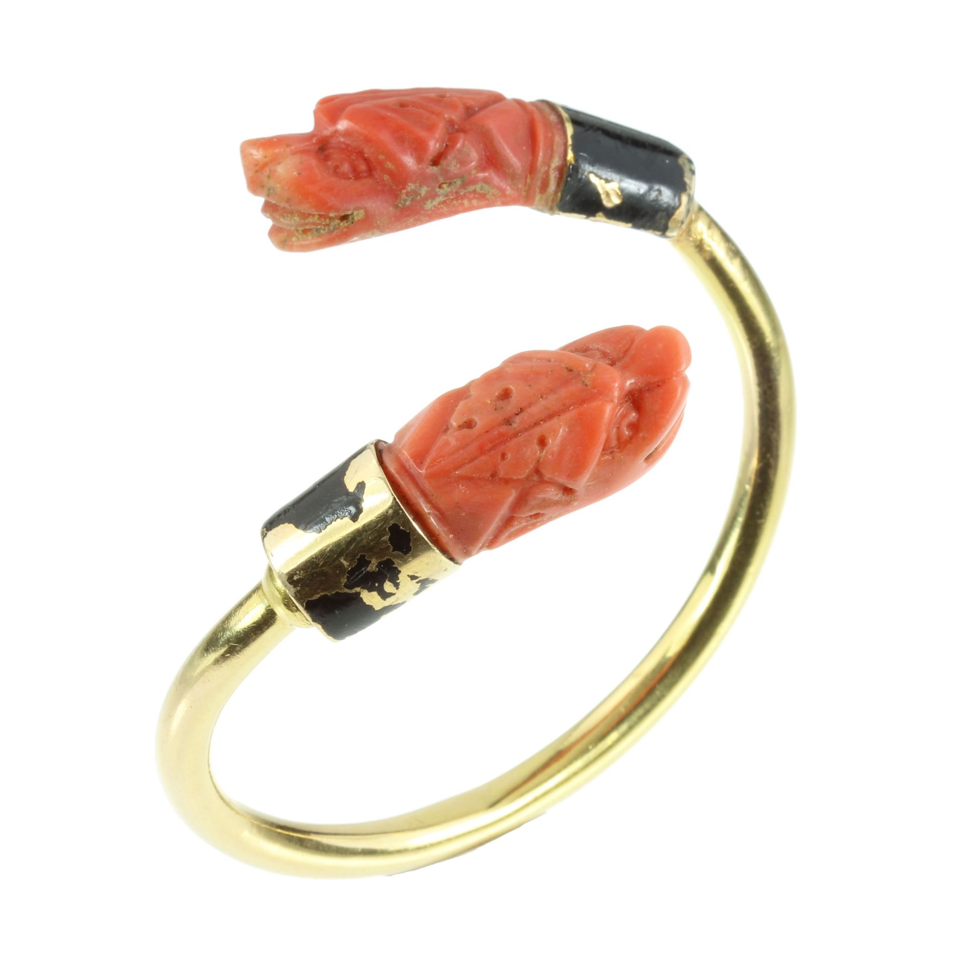 AN ANTIQUE ART DECO CARVED CORAL AND BLACK ENAMEL BANGLE in high carat yellow gold, the incomplete