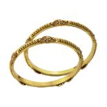 A PAIR OF BANGLES, SOUTH EAST ASIAN in 22ct yellow gold, each beaded motifs, stained red in parts,