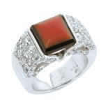 AN ART DECO CORAL, ONYX AND DIAMOND DRESS RING in 18ct white gold set with a central piece of