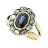 AN ANTIQUE SAPPHIRE AND DIAMOND CLUSTER RING in yellow gold and silver, set with an oval cut blue