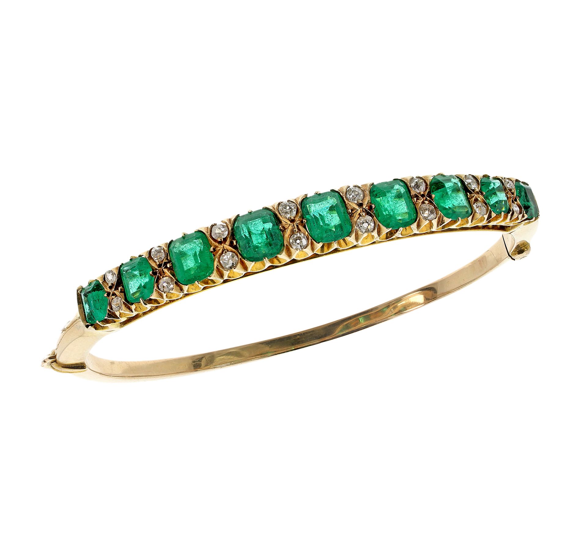 AN EMERALD AND DIAMOND BANGLE in yellow gold, set with a half hoop of graduated emerald cut emeralds