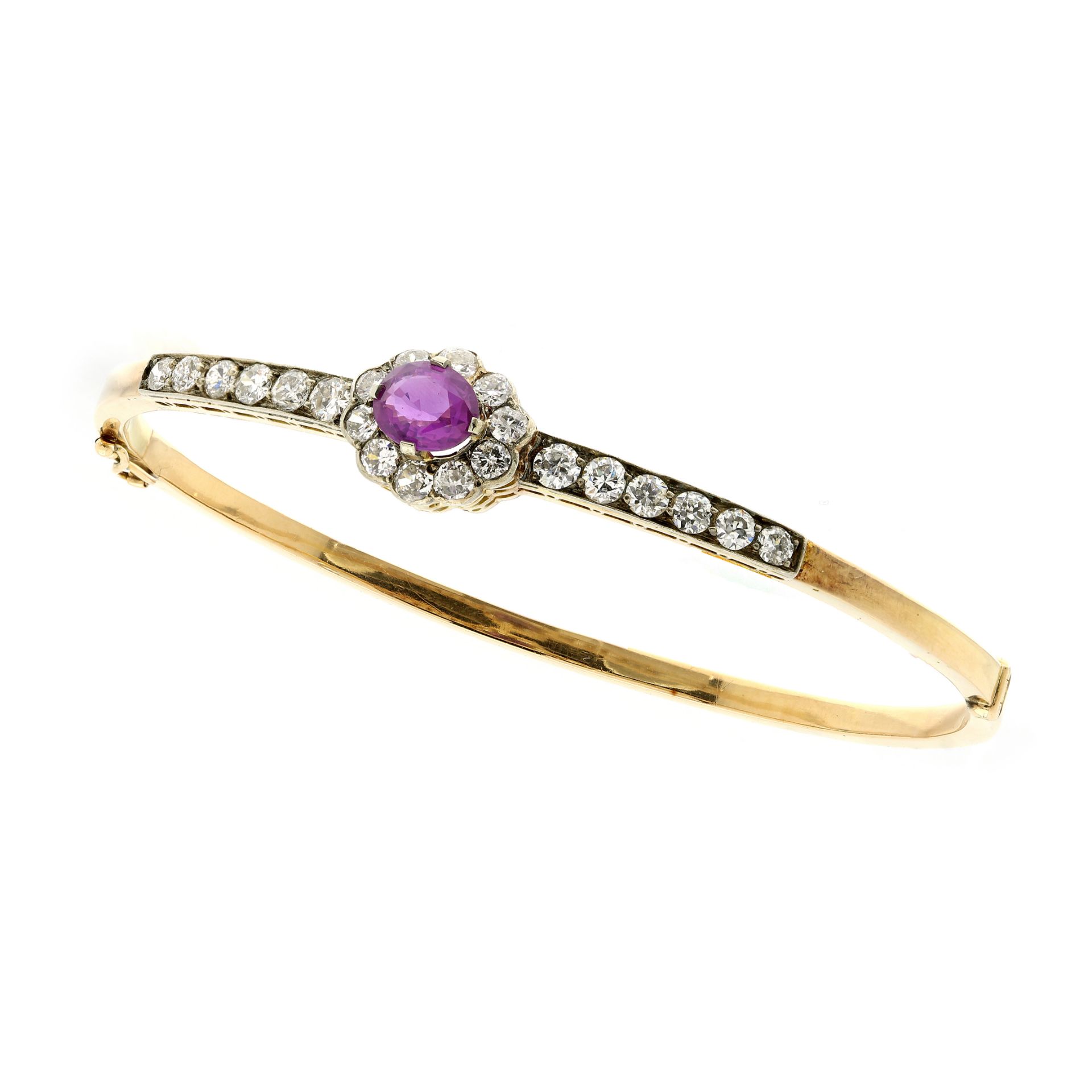 A PINK SAPPHIRE AND DIAMOND BANGLE in high carat yellow gold, set with a central oval cut pink