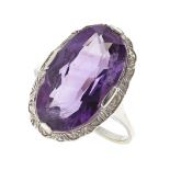 AN AMETHYST DRESS RING in white gold, set with a large oval cut amethyst within a bead decorated