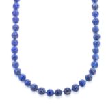 A CARVED LAPIS LAZULI BEAD NECKLACE comprising a single row of eighty carved and polished lapis
